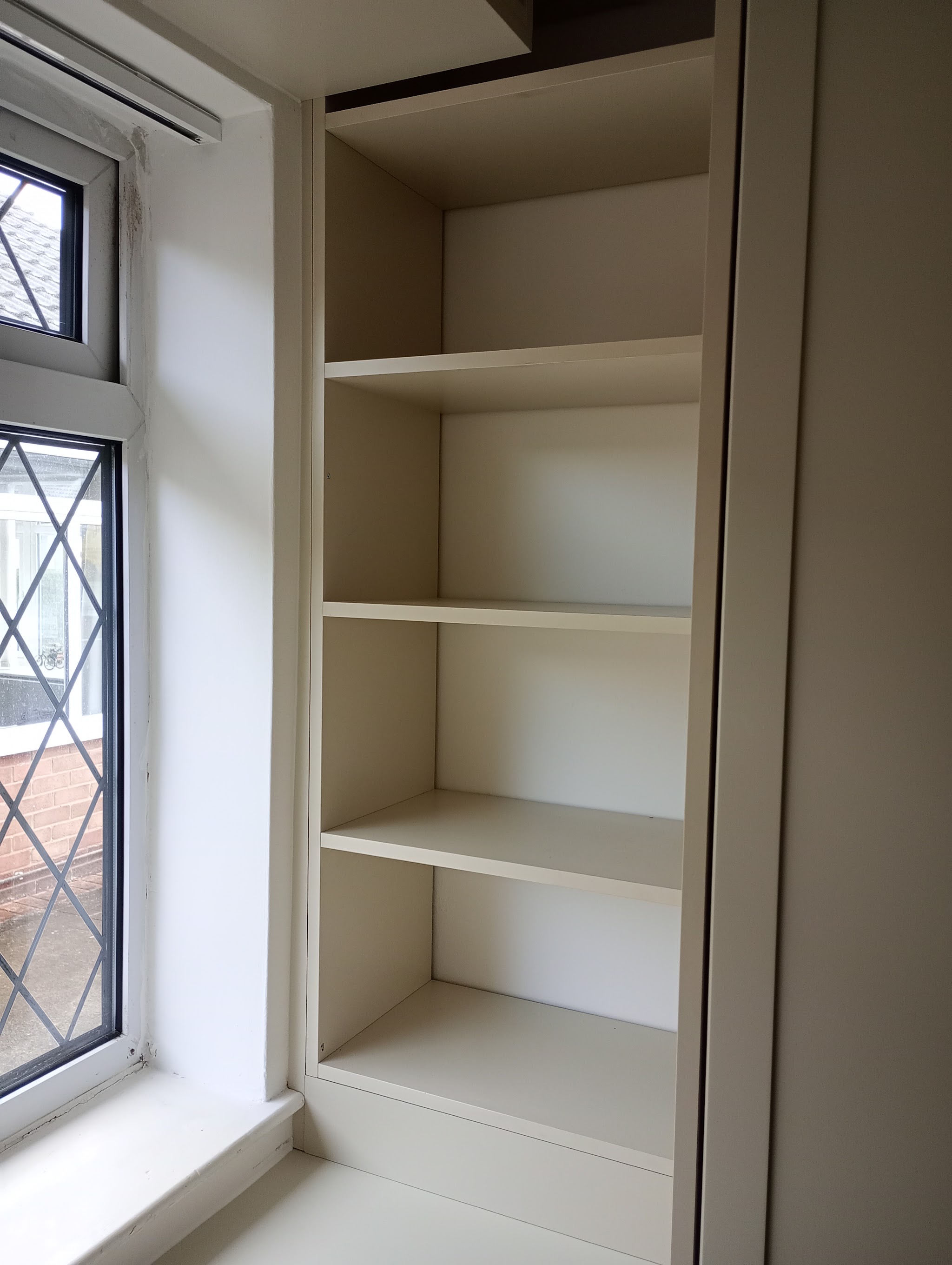 Built in shelving unit fitted beside a window