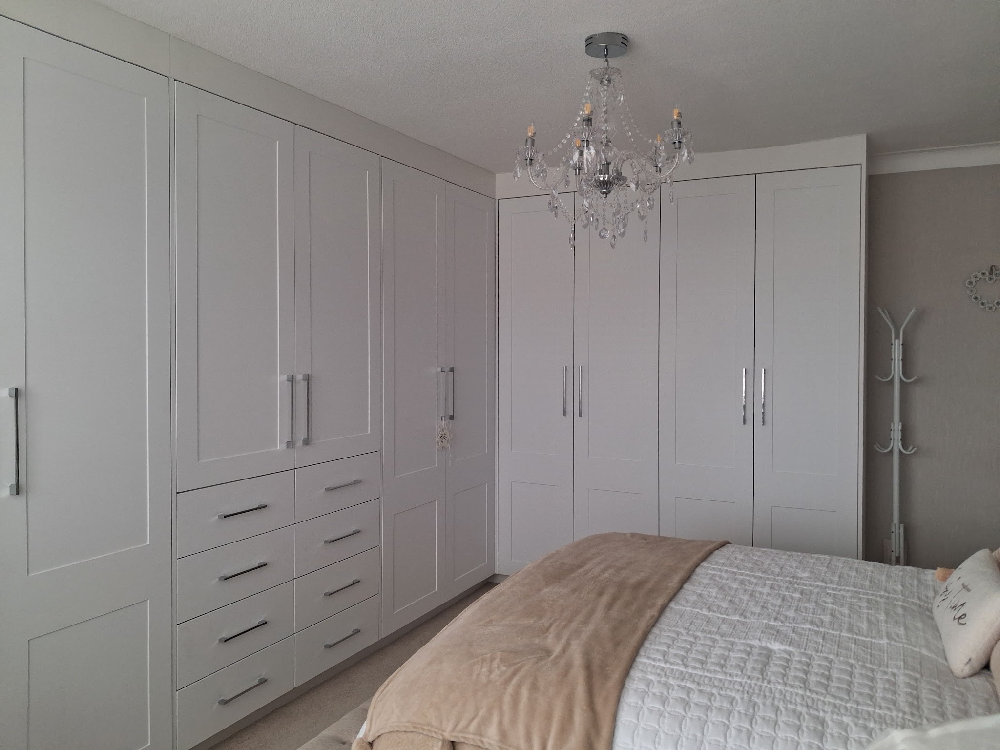 A full wall of white fitted wardrobes with a bank of drawers